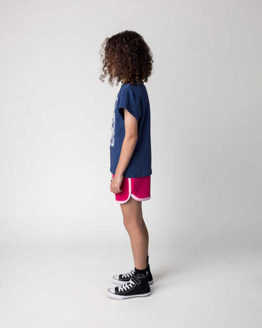 Kid wearing the Messy Bows Tee in ink with the Sprint Short in crimson and pink, side view