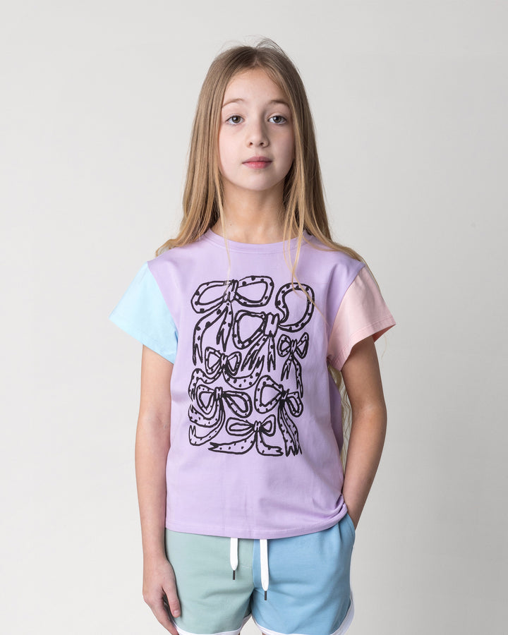 Close up of the Messy Bows Tee in lilac, aqua and pink on a kid, front view
