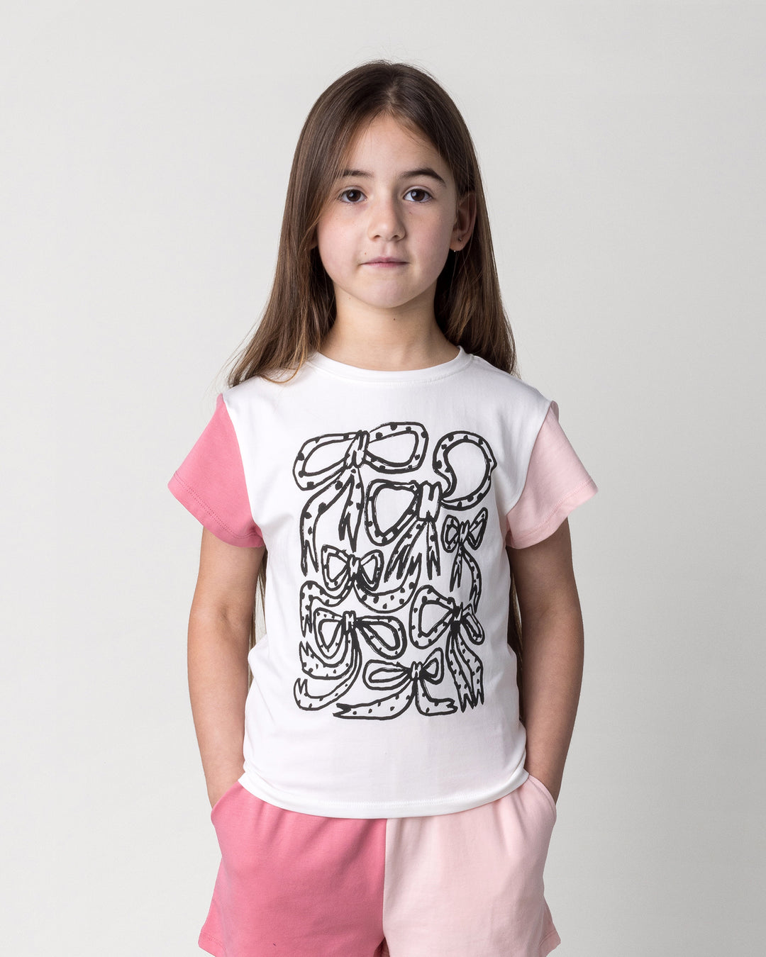Close up of the Messy Bows Tee in white and pinks on a kid, front view