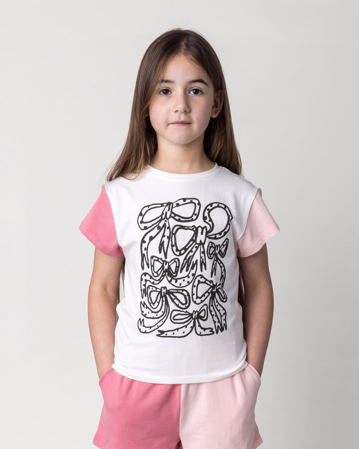 Close up of the Messy Bows Tee in white and pinks on a kid, front view