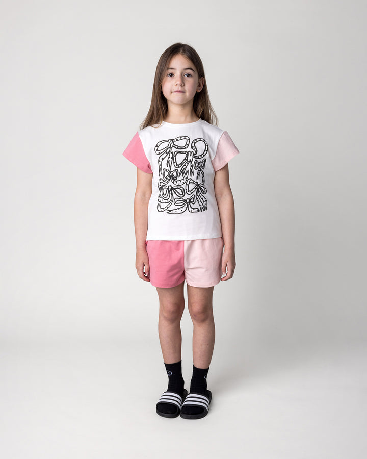 Kid wearing the Messy Bows Tee in white and pinks with the Two Tone Short in pinks, front view