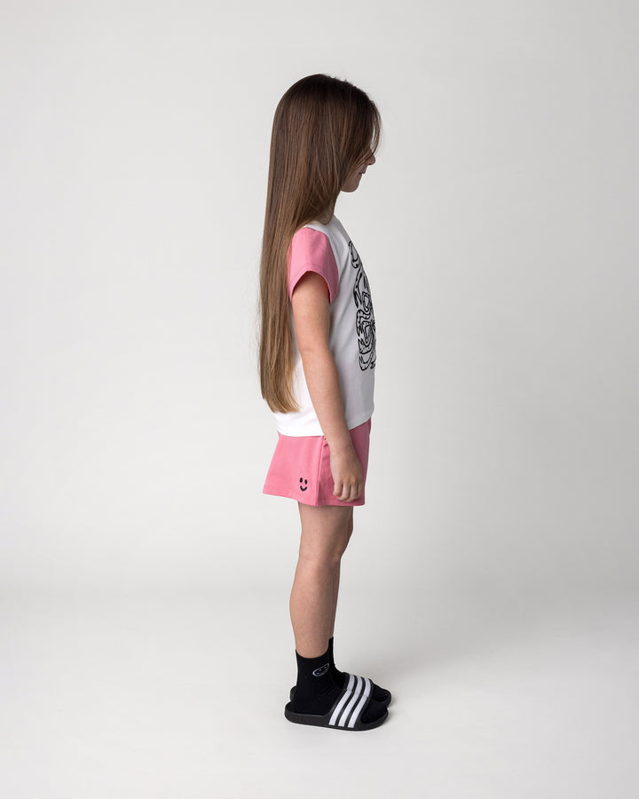 Kid wearing the Messy Bows Tee in white and pinks with the Two Tone Short in pinks, side view