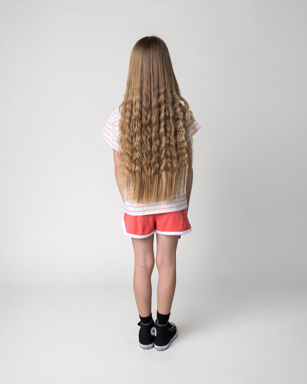 Kid wearing the Super Duper Cool Tee in marle and coral stripe with the Track Star Short in tangerine, back view