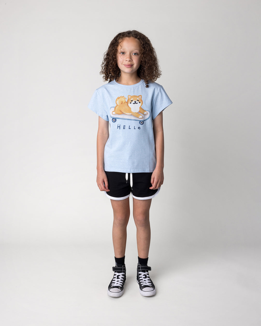 Kid wearing the Skate Puppy Tee in light blue marle with the Sprint Short in black and white, front view