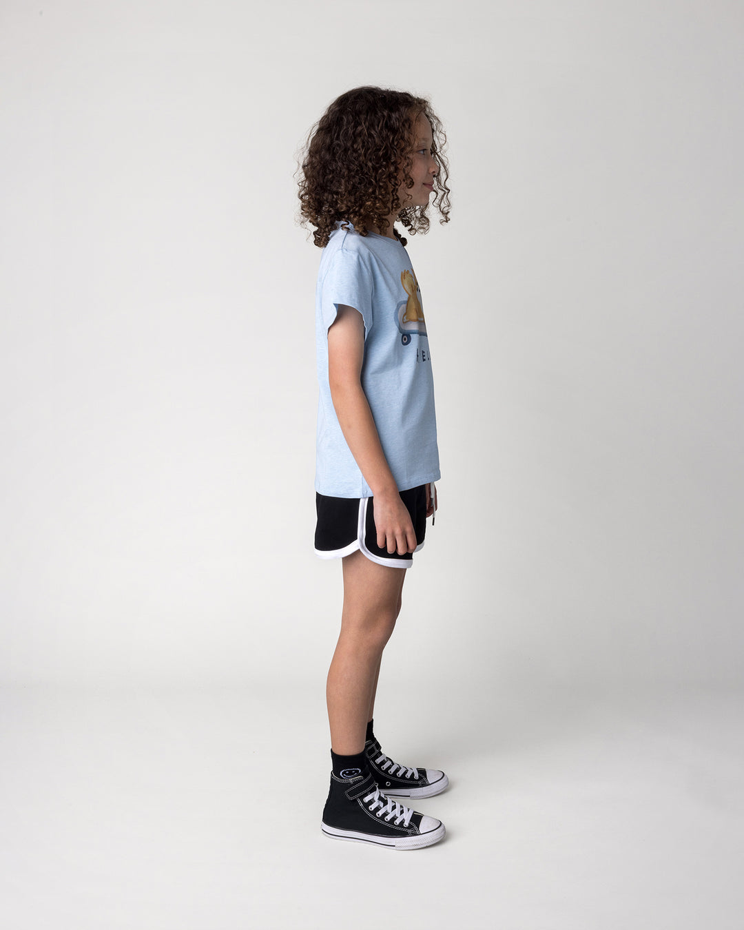Kid wearing the Skate Puppy Tee in light blue marle with the Sprint Short in black and white, side view