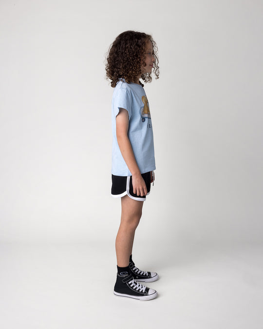 Kid wearing the Skate Puppy Tee in light blue marle with the Sprint Short in black and white, side view