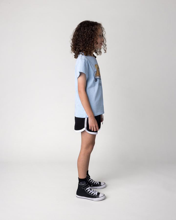 Kid wearing the Skate Puppy Tee in light blue marle with the Sprint Short in black and white, side view