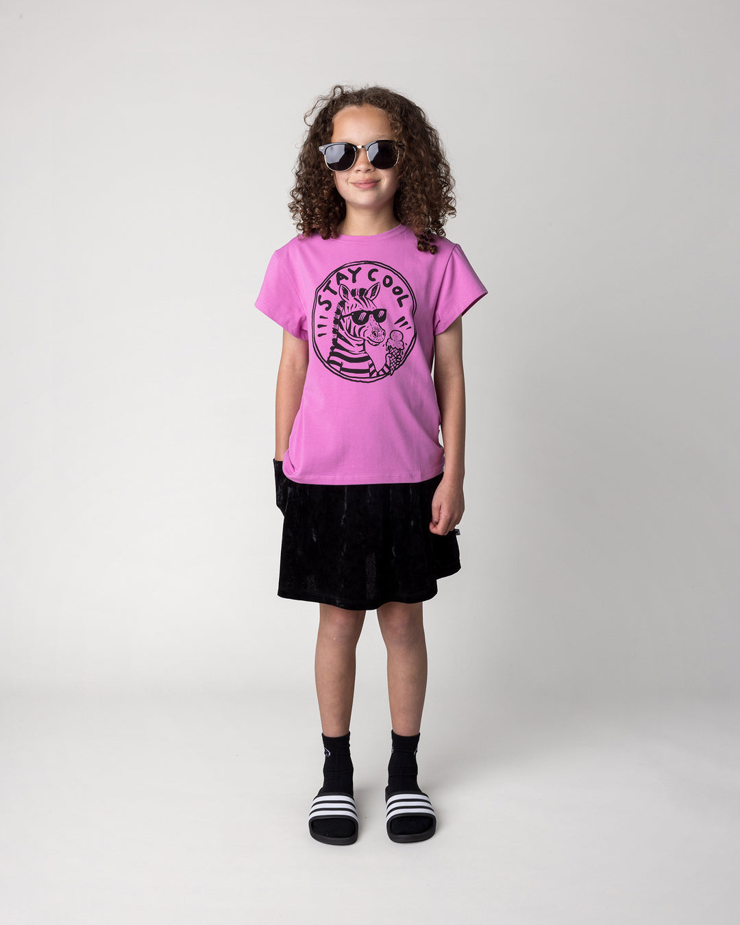 Kid wearing the Stay Cool Tee in violet with the Velvet Skirt in black, front view