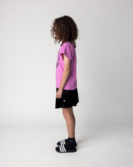Kid wearing the Stay Cool Tee in violet with the Velvet Skirt in black, side view