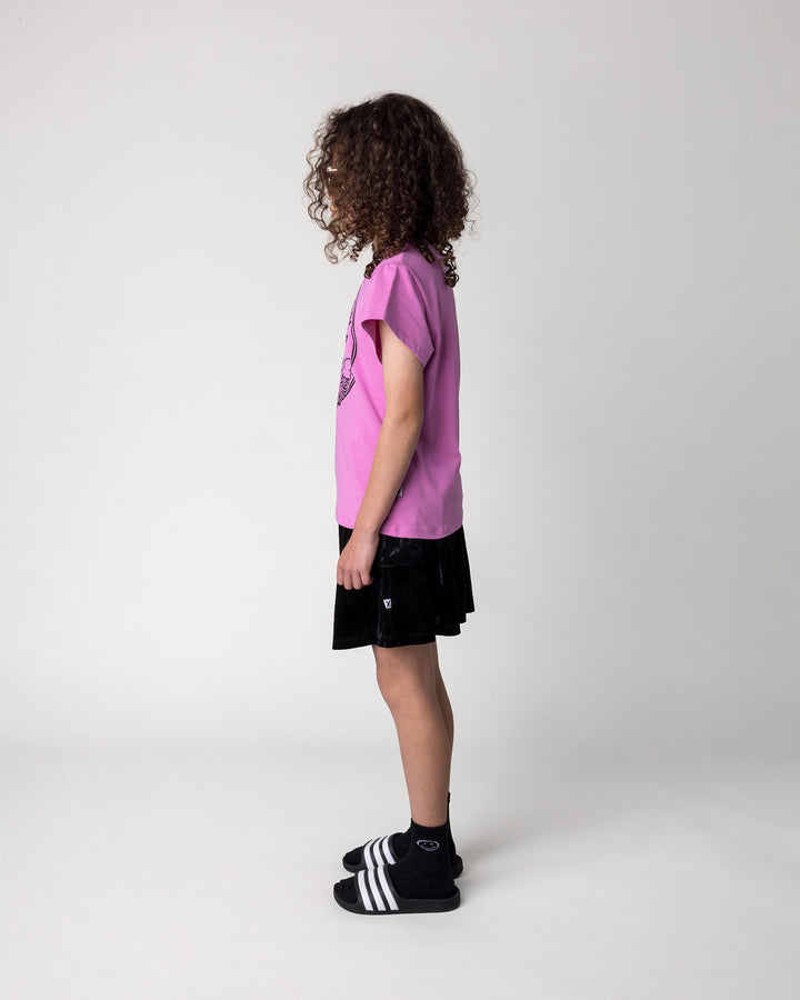Kid wearing the Stay Cool Tee in violet with the Velvet Skirt in black, side view