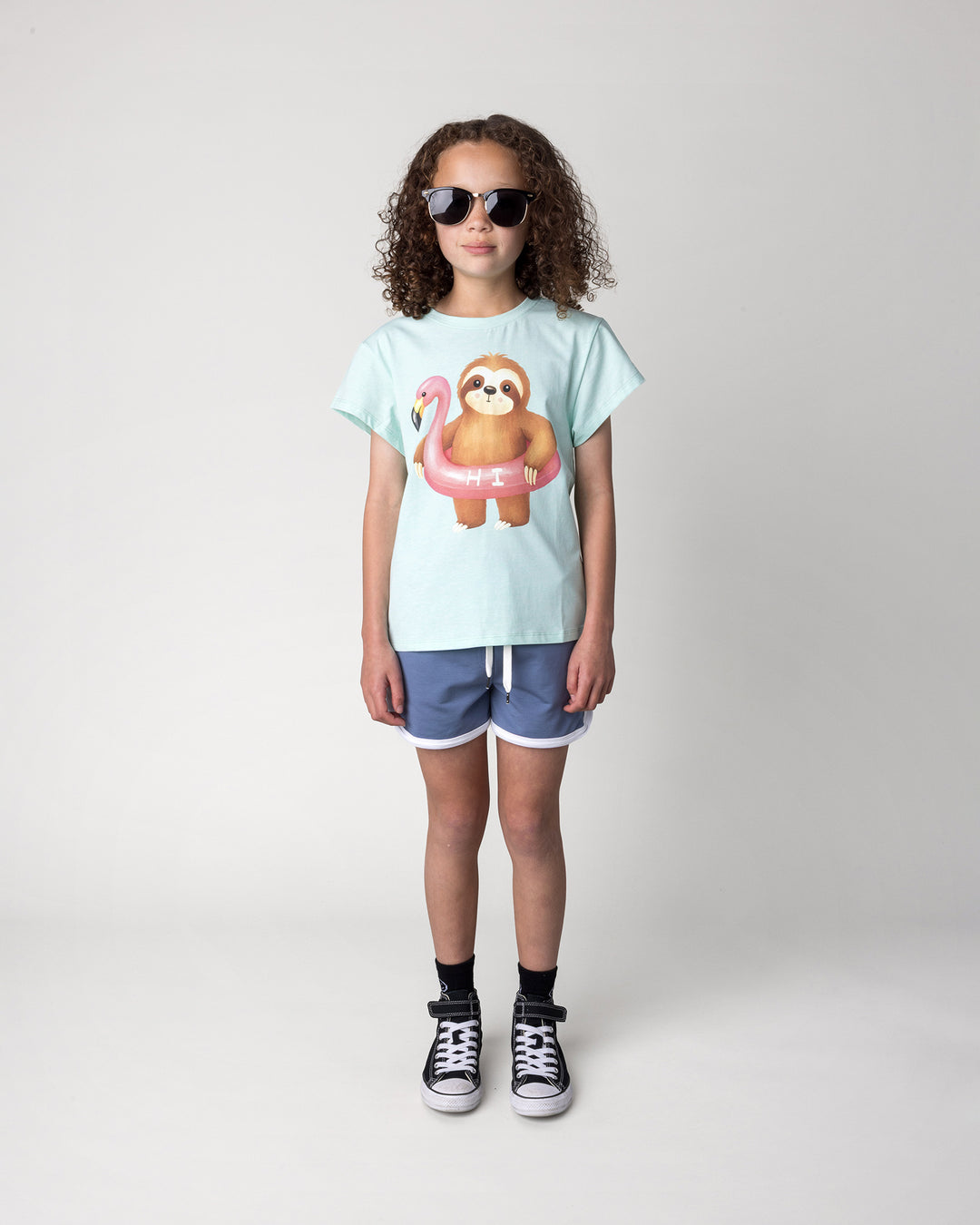 Kid wearing the Swimming Sloth Tee in mint marle with the Sprint Short in cornflower and white, front view