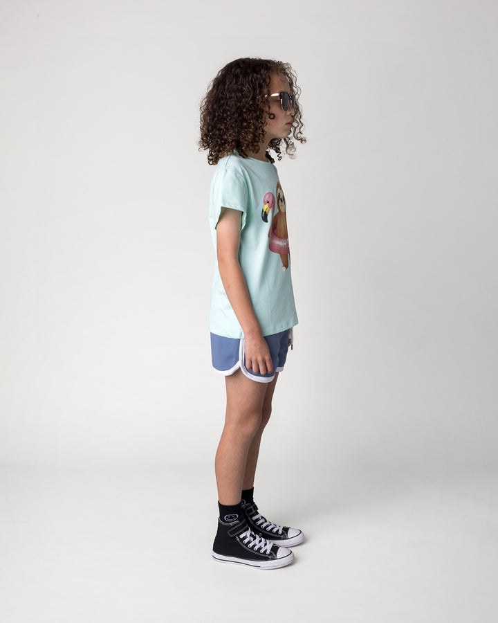 Kid wearing the Swimming Sloth Tee in mint marle with the Sprint Short in cornflower and white, side view