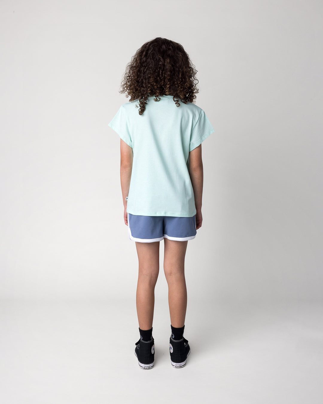 Kid wearing the Swimming Sloth Tee in mint marle with the Sprint Short in cornflower and white, back view
