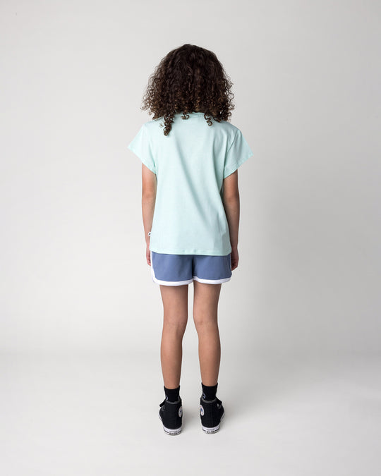 Kid wearing the Swimming Sloth Tee in mint marle with the Sprint Short in cornflower and white, back view