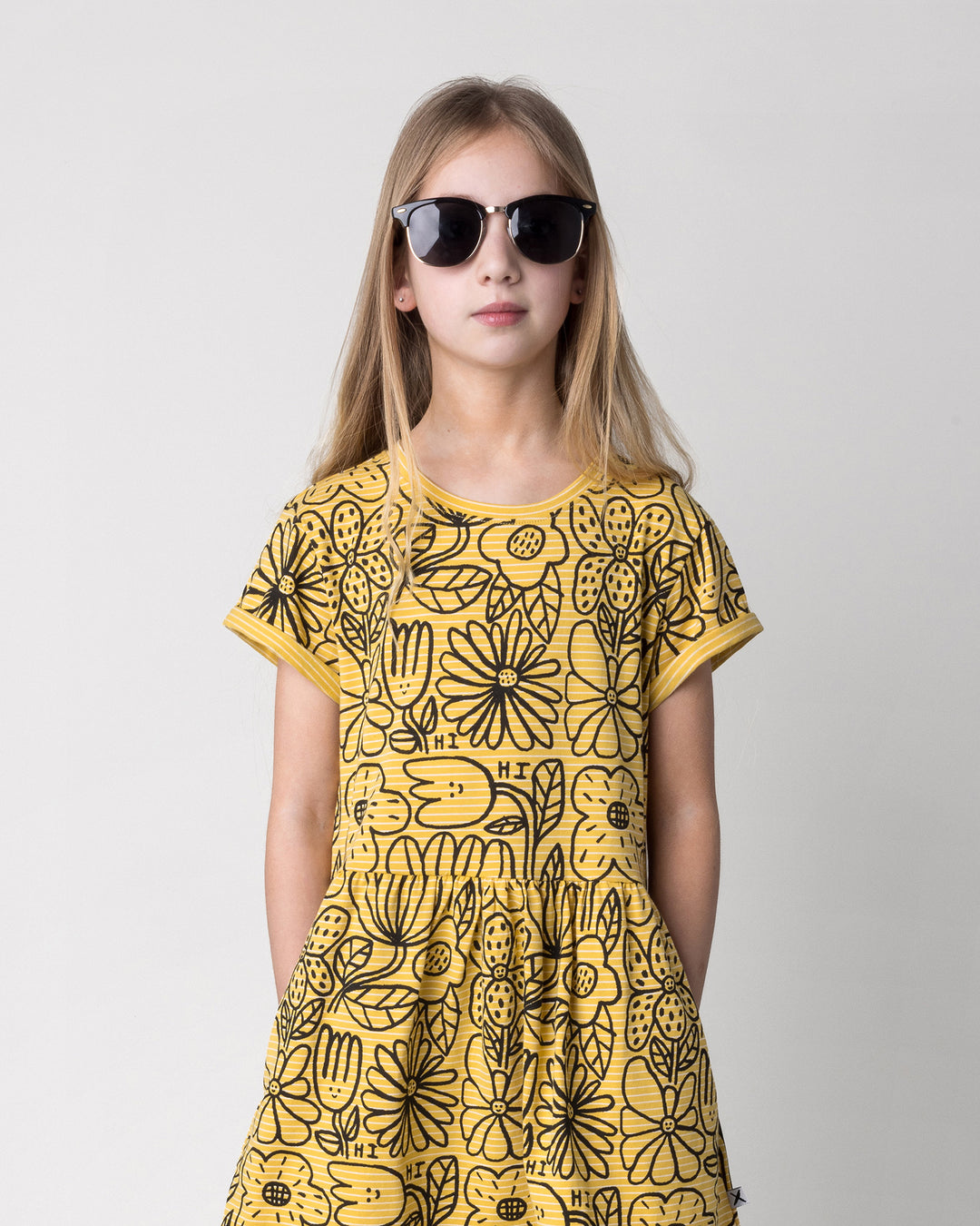 Close up of the Big Flowers Dress in mustard stripe on a kid, front view