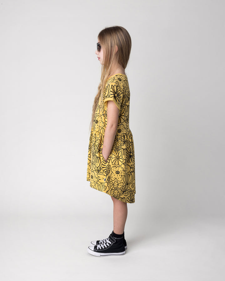 Kid wearing the Big Flowers Dress in mustard stripe, side view