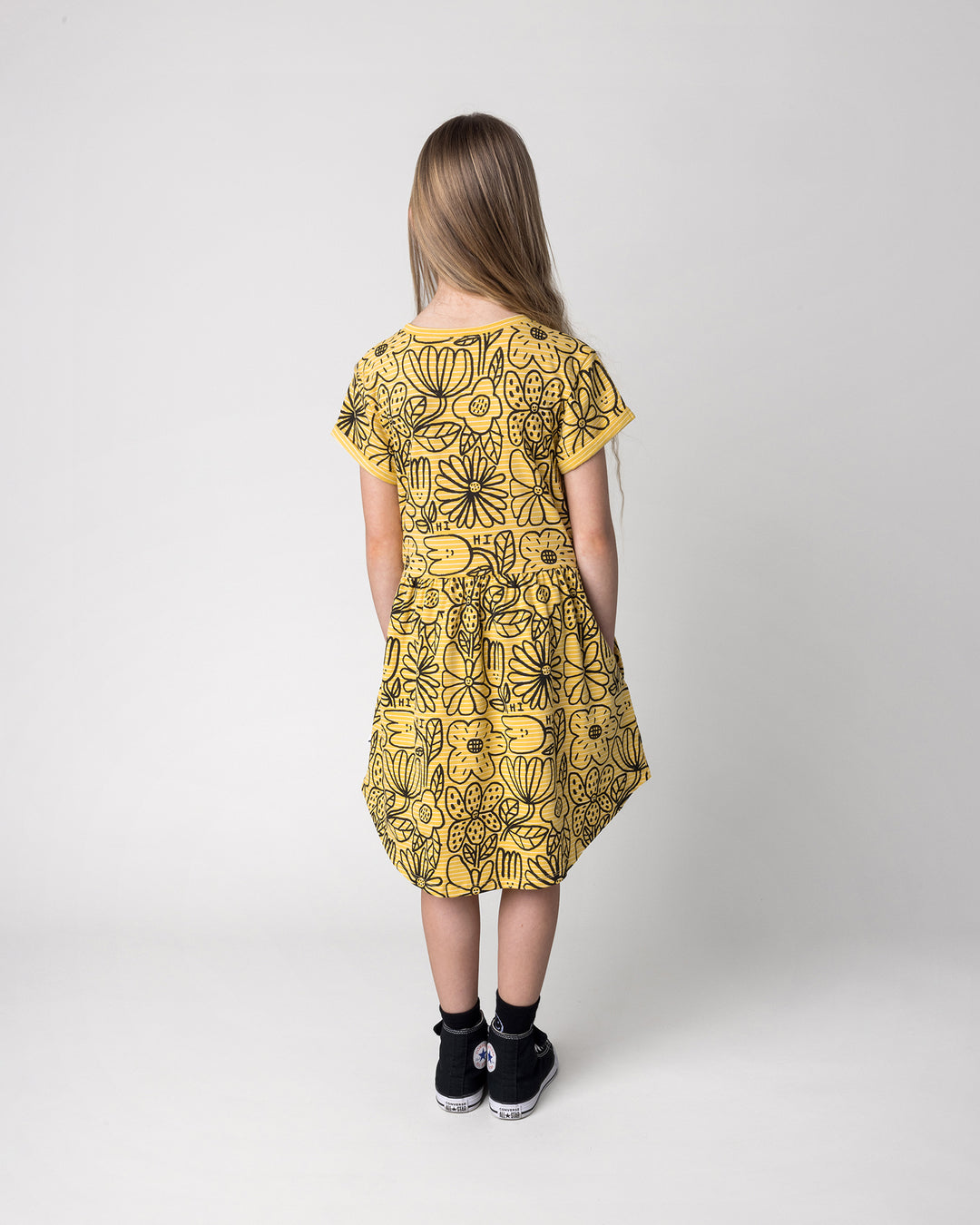 Kid wearing the Big Flowers Dress in mustard stripe, back view