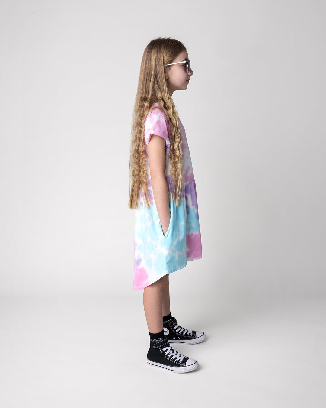 Kid wearing the Pocket Flower Dress in tie dye, side view
