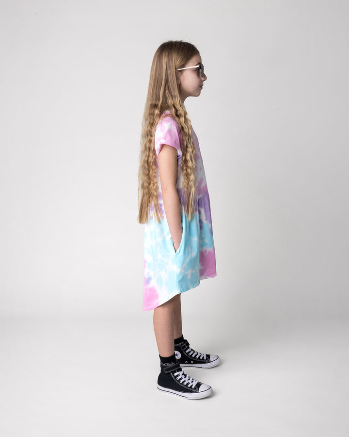 Kid wearing the Pocket Flower Dress in tie dye, side view