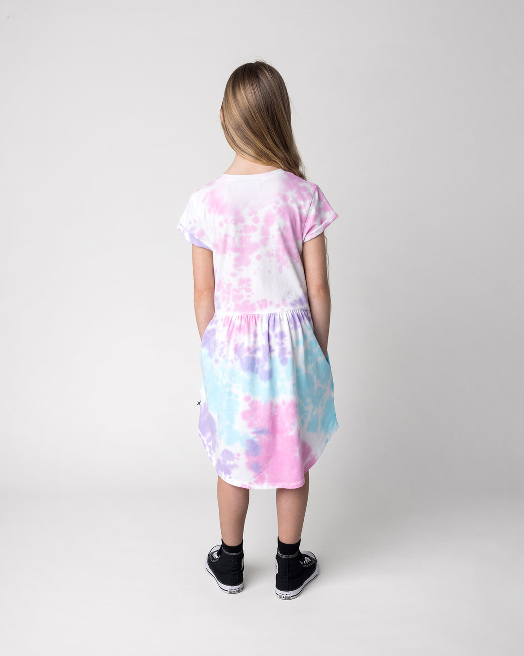Kid wearing the Pocket Flower Dress in tie dye, back view