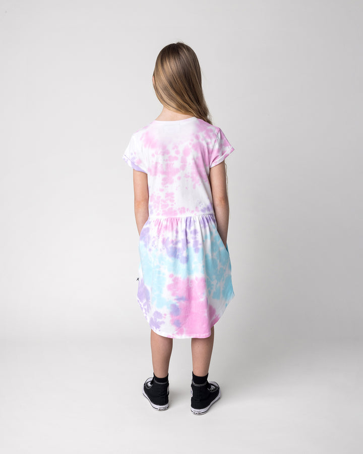 Kid wearing the Pocket Flower Dress in tie dye, back view