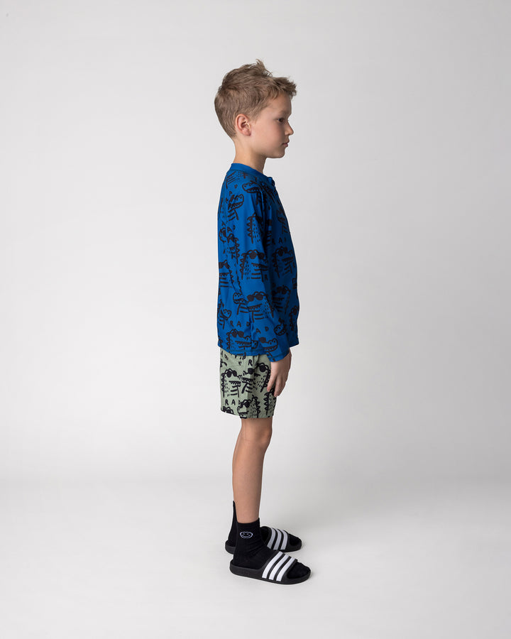 Kid wearing the Rad Croc Rashie in midnight with the Rad Croc Boardies in khaki, side view