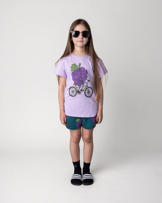 Kid wearing the Biking Grape Tee in lilac with the Biking Grape Short in dark teal, front view