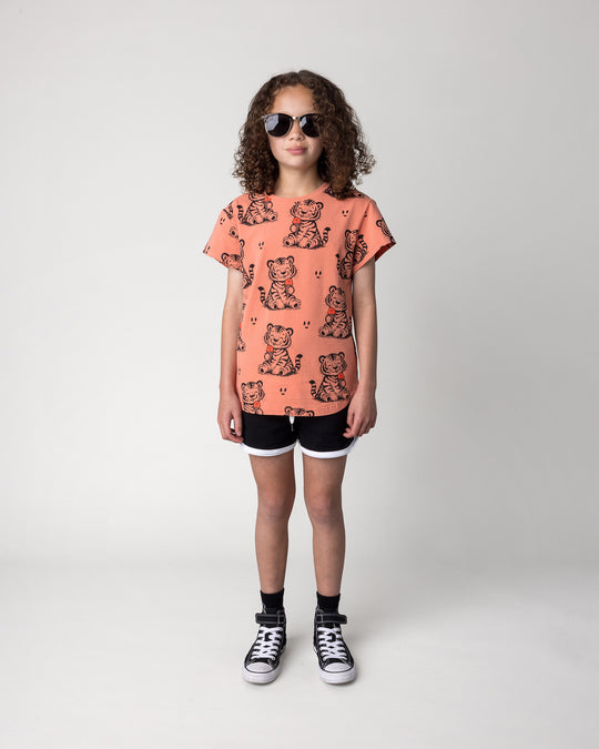 Kid wearing the Happy Tiger Tee in apricot with the Sprint Short in black and white, front view