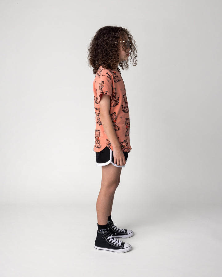 Kid wearing the Happy Tiger Tee in apricot with the Sprint Short in black and white, side view