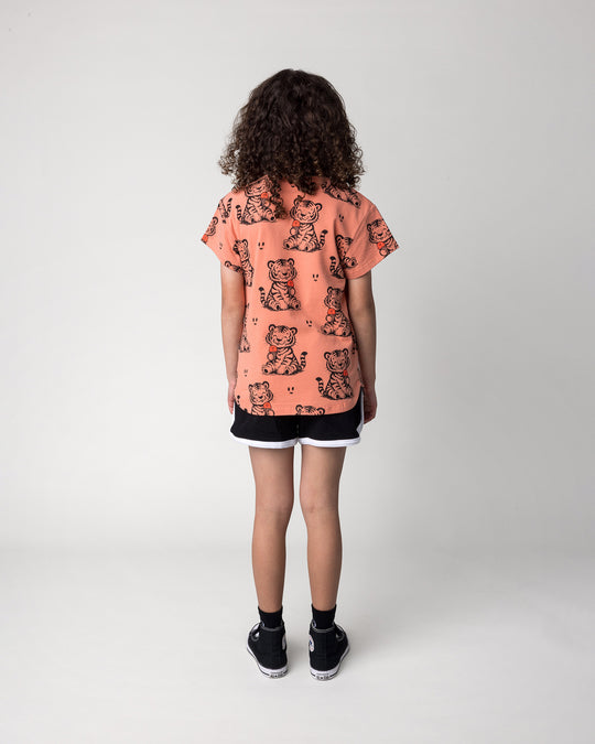 Kid wearing the Happy Tiger Tee in apricot with the Sprint Short in black and white, back view