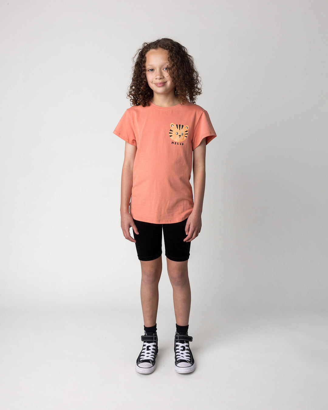 Kid wearing the Hello Tiger Tee in apricot with the Velvet Bike Pant in black, front view
