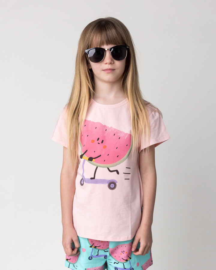 Close up of the Scooting Watermelon Tee in light pink on a kid, front view