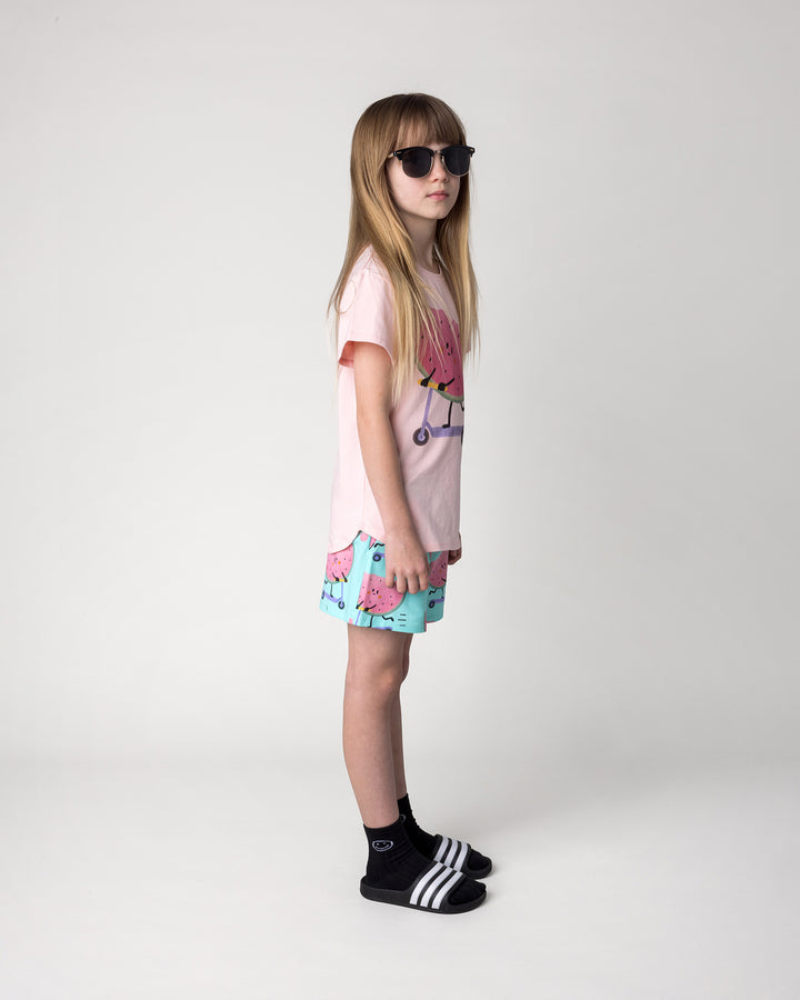 Kid wearing the Scooting Watermelon Tee in light pink with the Scooting Watermelon Short in light mint, side view