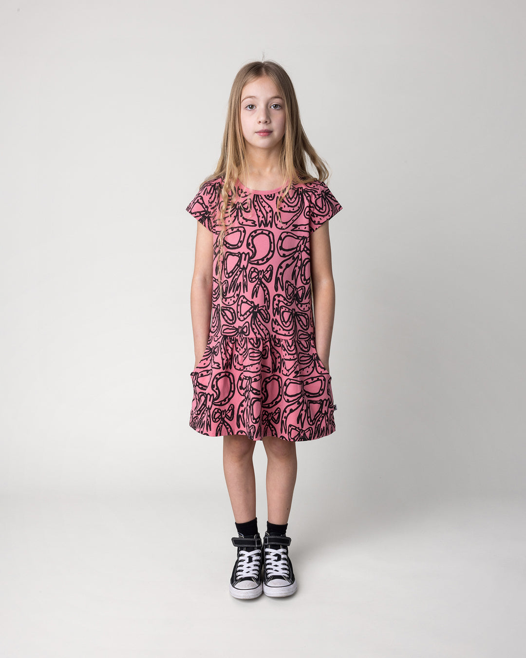 Kid wearing the Big Bows Dress in candy, front view