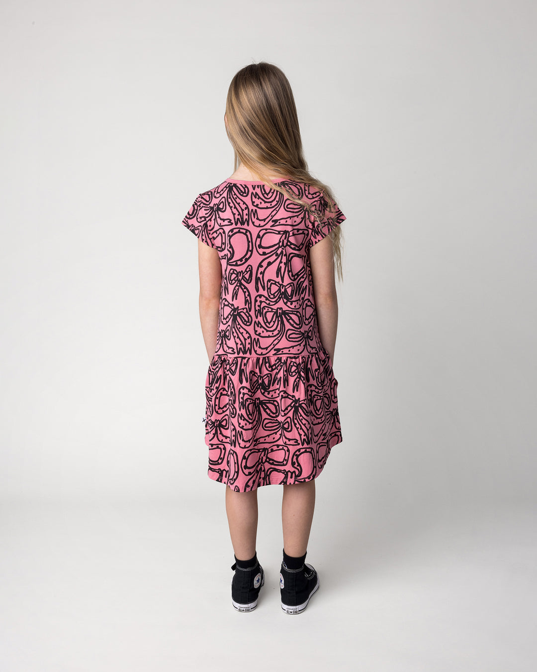 Kid wearing the Big Bows Dress in candy, back view