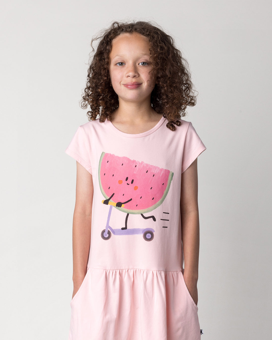 Close up of the Scooting Watermelon Dress in light pink on a kid, front view