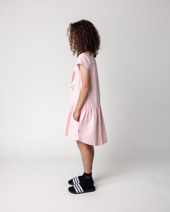 Kid wearing the Scooting Watermelon Dress in light pink, side view