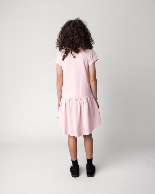 Kid wearing the Scooting Watermelon Dress in light pink, back view