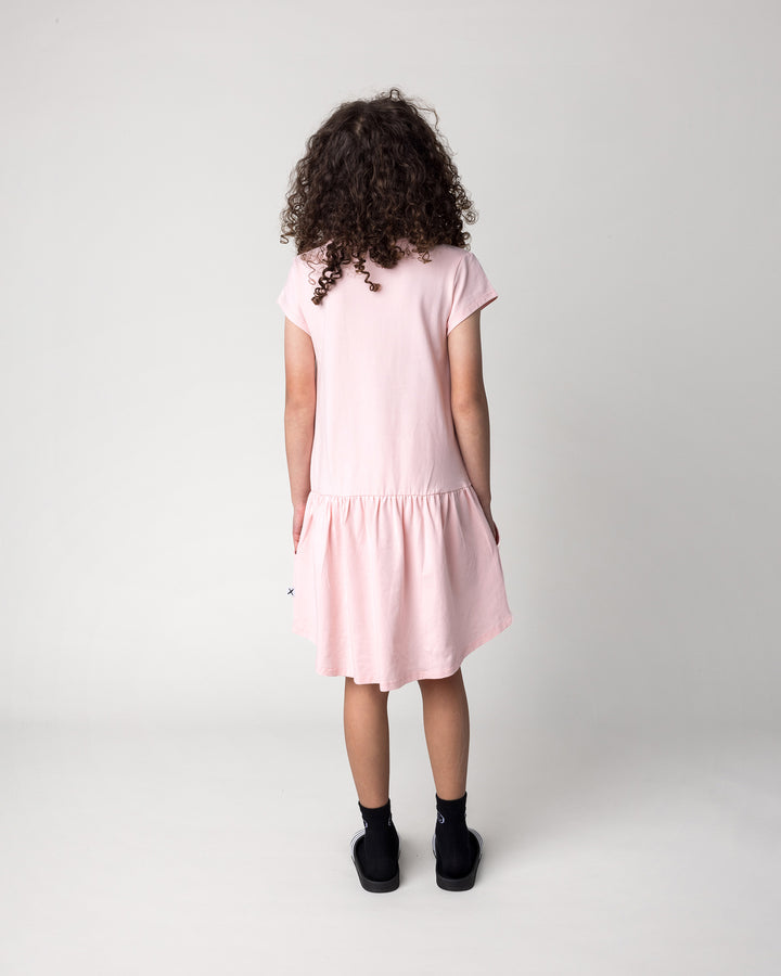 Kid wearing the Scooting Watermelon Dress in light pink, back view