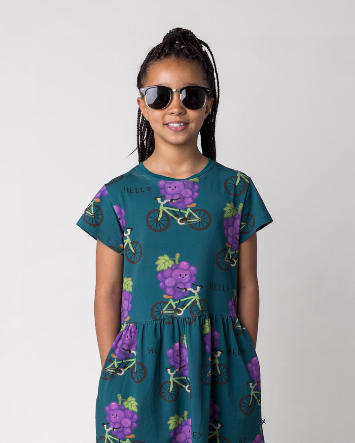 Close up of the Biking Grape Dress in dark teal on a kid, front view