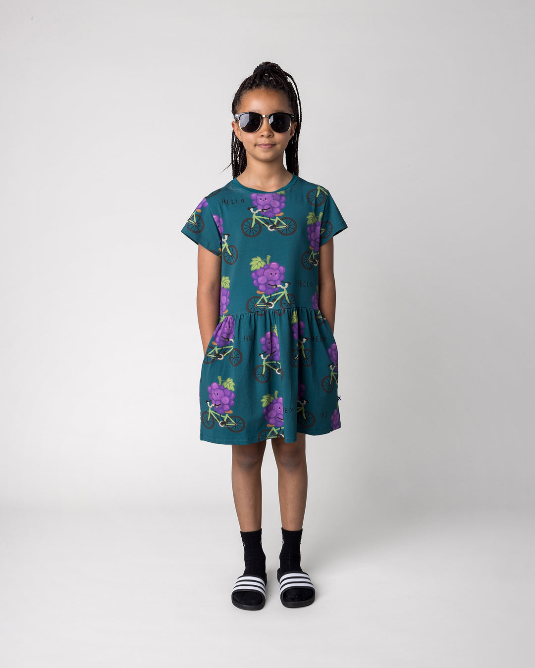 Kid wearing the Biking Grape Dress in dark teal, front view