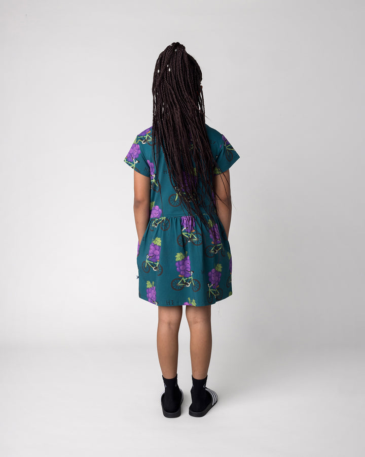Kid wearing the Biking Grape Dress in dark teal, back view