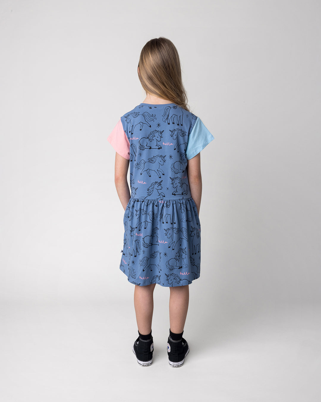 Kid wearing the Hello Unicorns Dress in mid blue, light blue and pink, back view