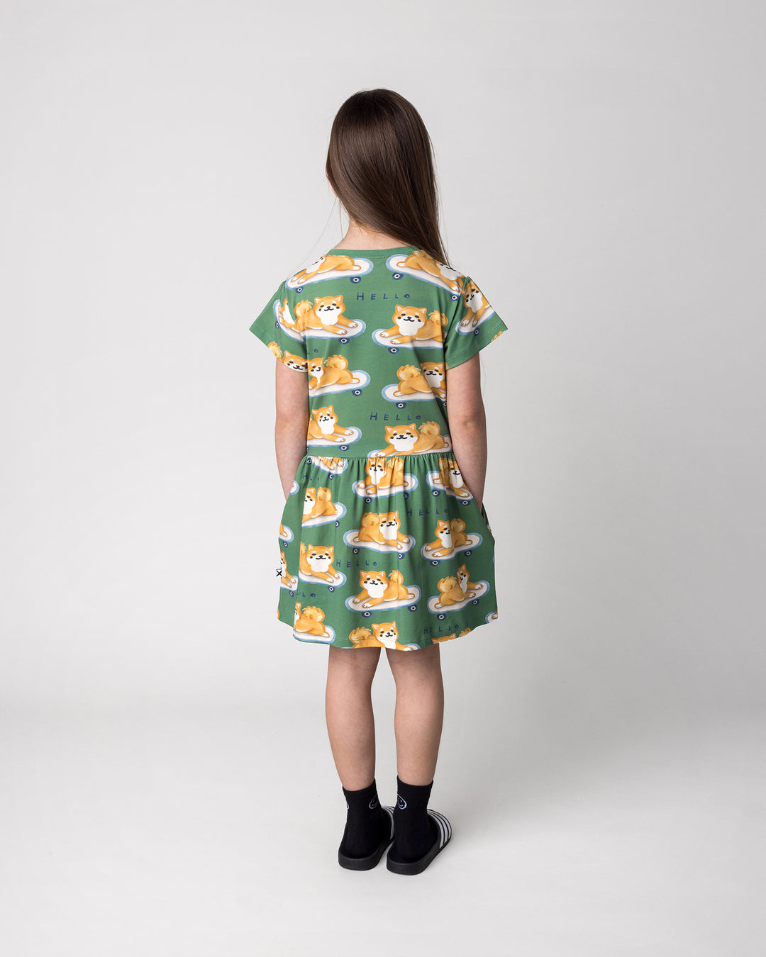 Kid wearing the Skate Puppy Dress in turf, back view