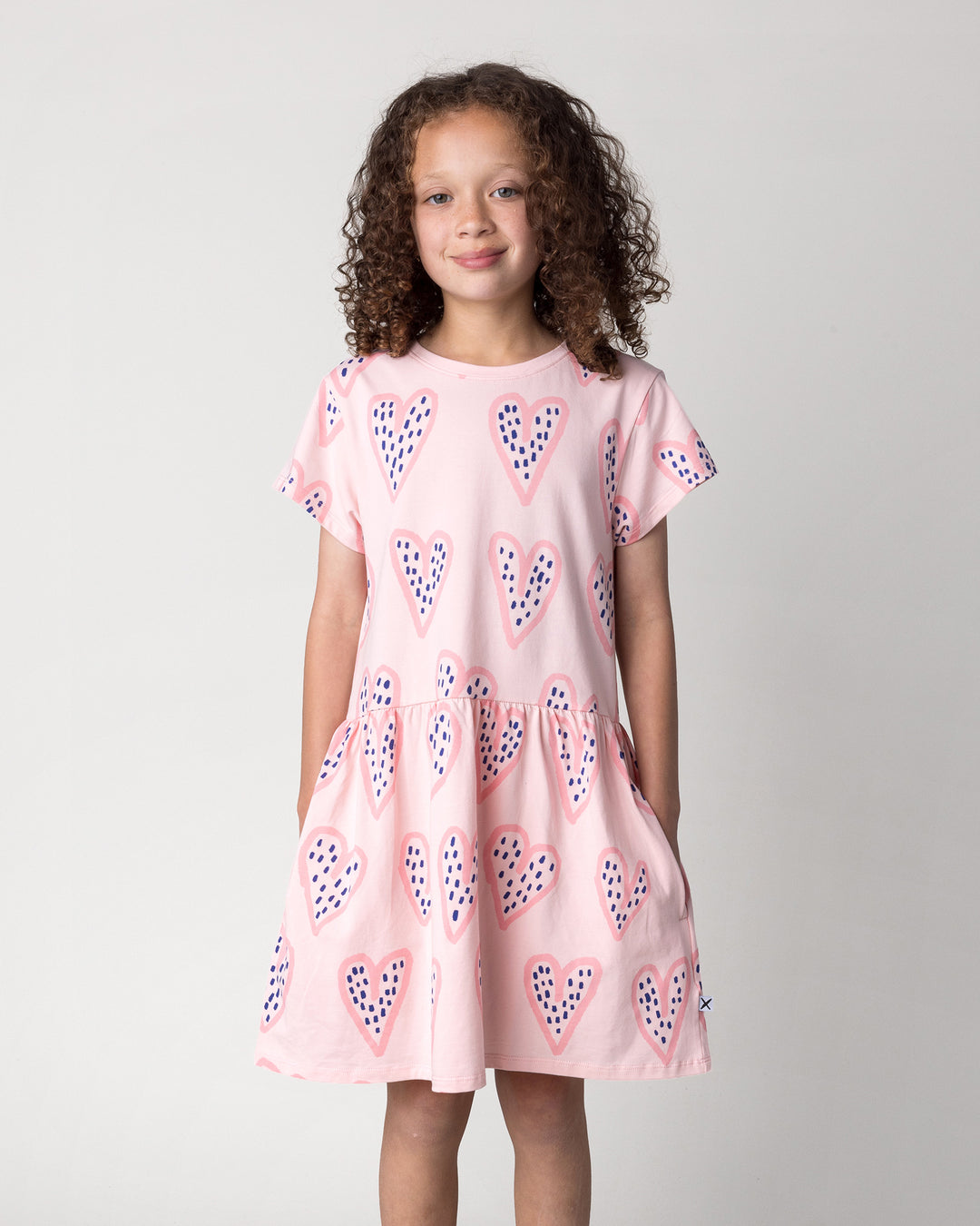 Close up of the Speckle Heart Dress in pink on a kid, front view