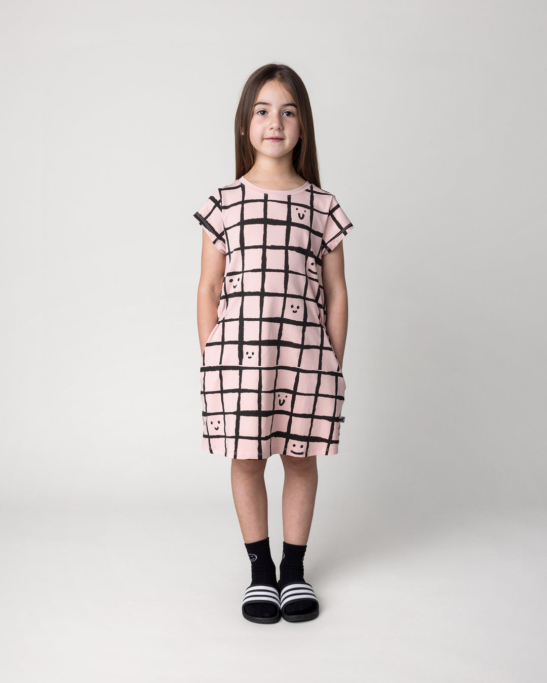 Kid wearing the Happy Squares Dress in dusty pink, front view