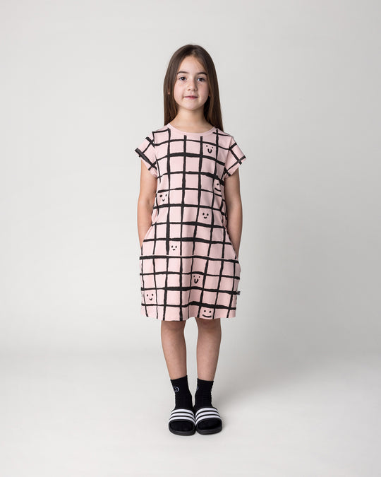 Kid wearing the Happy Squares Dress in dusty pink, front view