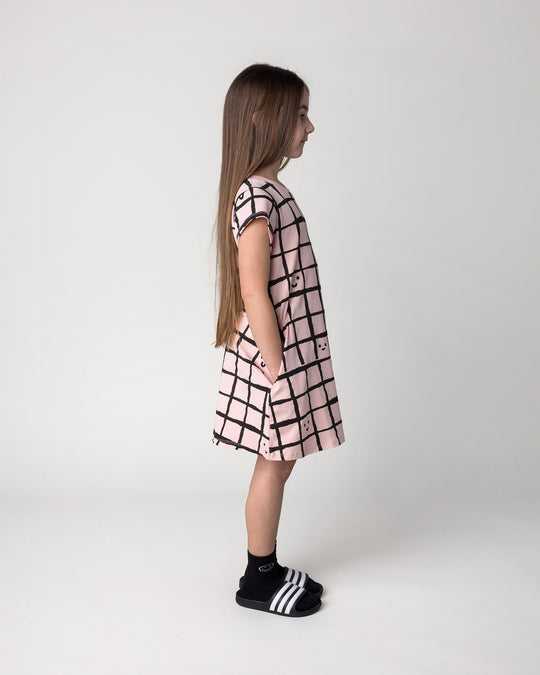 Kid wearing the Happy Squares Dress in dusty pink, side view