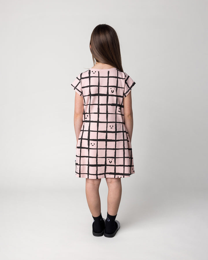 Kid wearing the Happy Squares Dress in dusty pink, back view