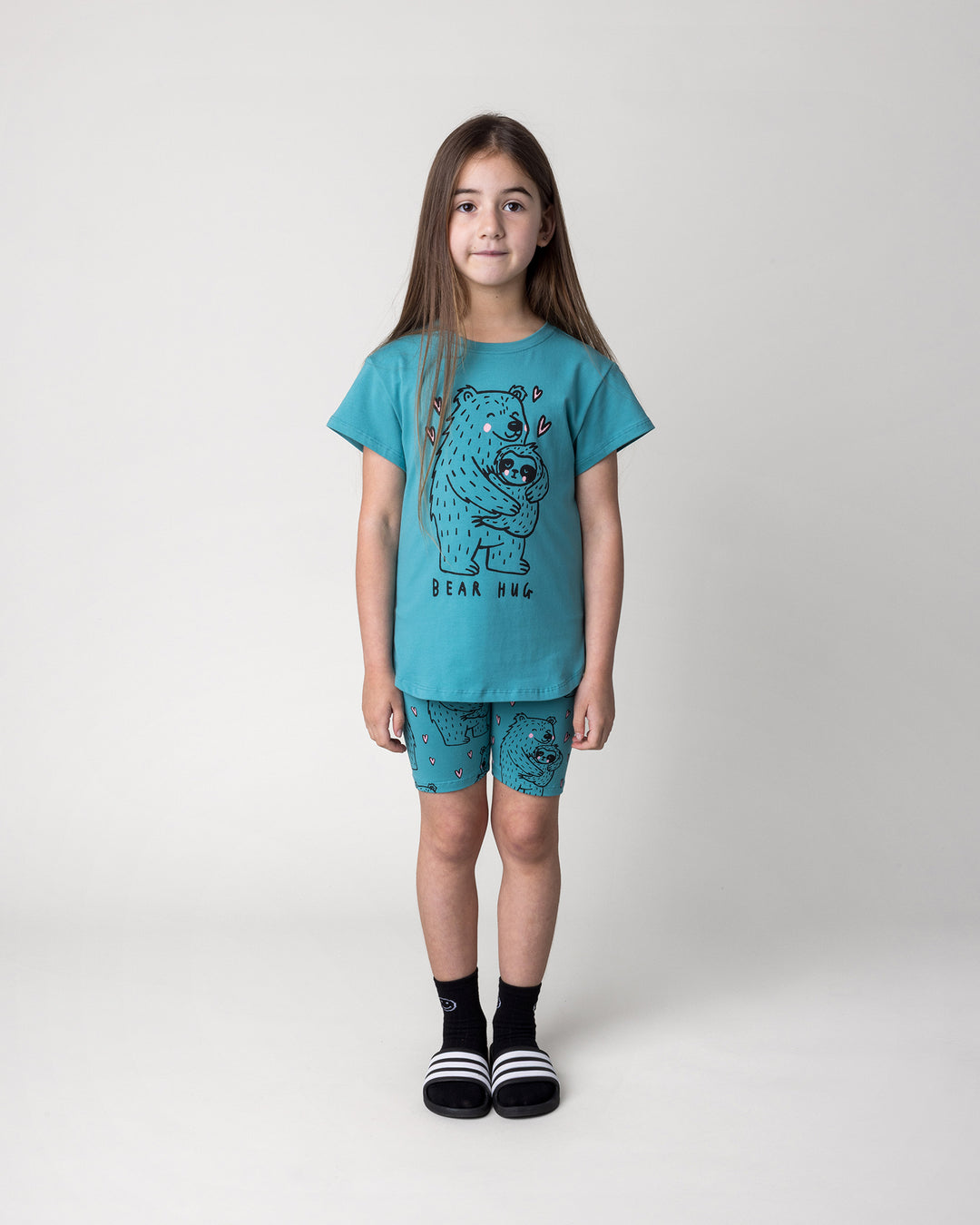 Kid wearing the Bear Hug Bike Pant in emerald with the Bear Hug Tee in emerald, front view